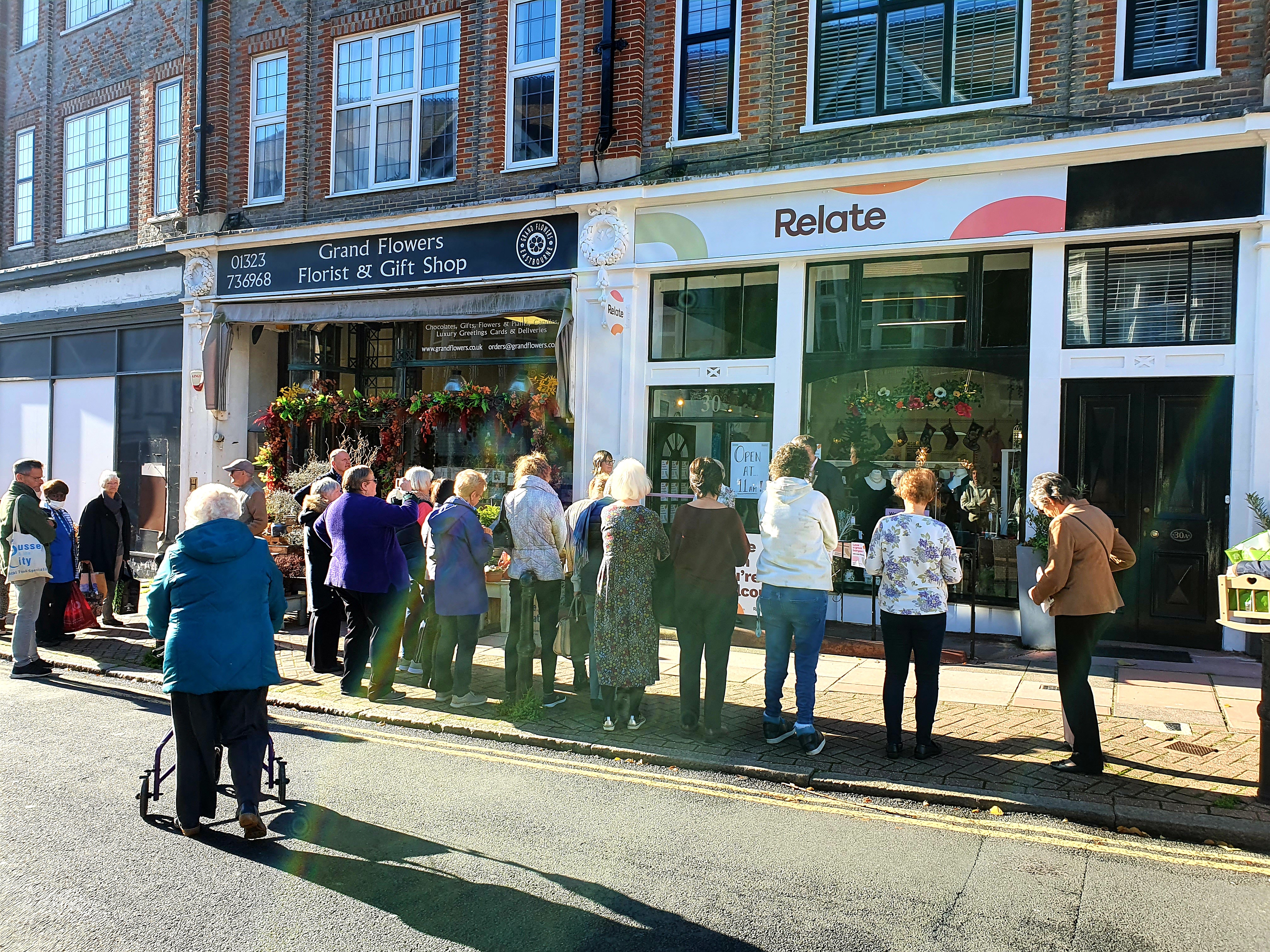 Crowd of people outside a charity shop, the sun is shining