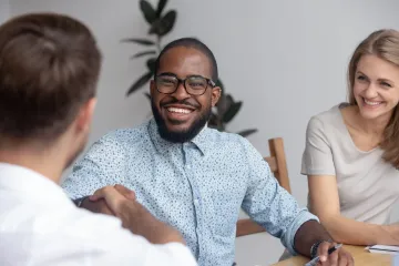 Heterosexual couple greeting male counsellor and smiling