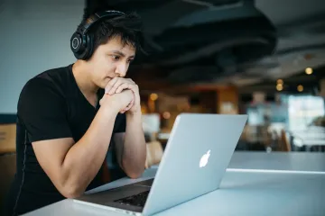 Young dark haired man looking at a laptop